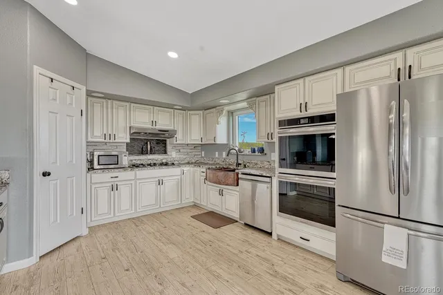 a large kitchen with stainless steel appliances granite countertop a stove a sink and white cabinets