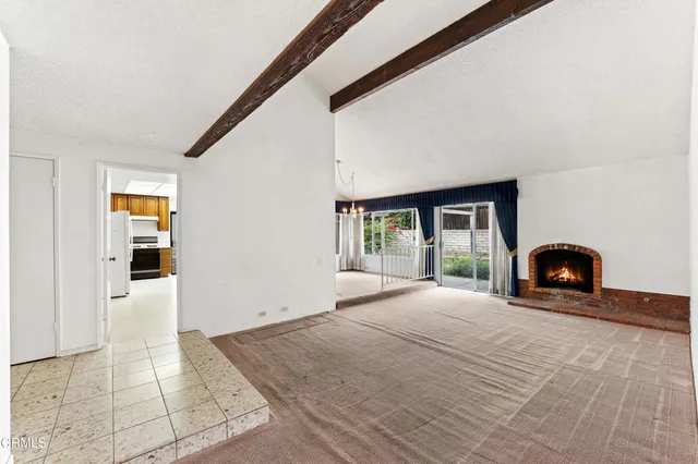a view of an empty room with a fireplace and a window