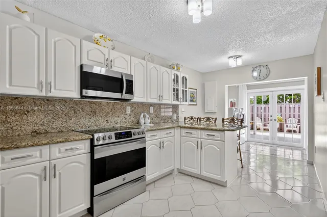 a kitchen with granite countertop white cabinets and stainless steel appliances