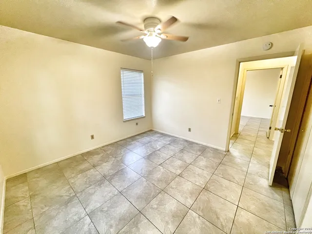 a view of an empty room and chandelier fan