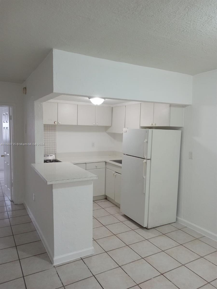 1230 West 54th Street, Unit 216A Hialeah, FL 33012 - Photo 11 of 28 a kitchen with cabinets and white appliances