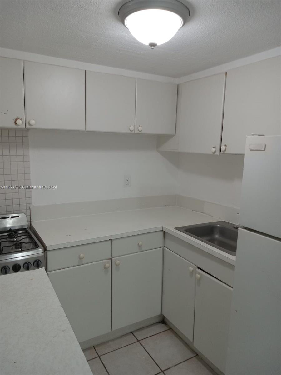 1230 West 54th Street, Unit 216A Hialeah, FL 33012 - Photo 13 of 28 a kitchen with white cabinets and a sink