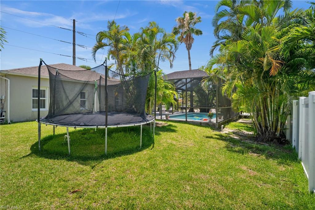 2017 Cape Coral Parkway West Cape Coral, FL 33914 - Photo 9 of 35 View of green lawn with a trampoline and an outdoor pool