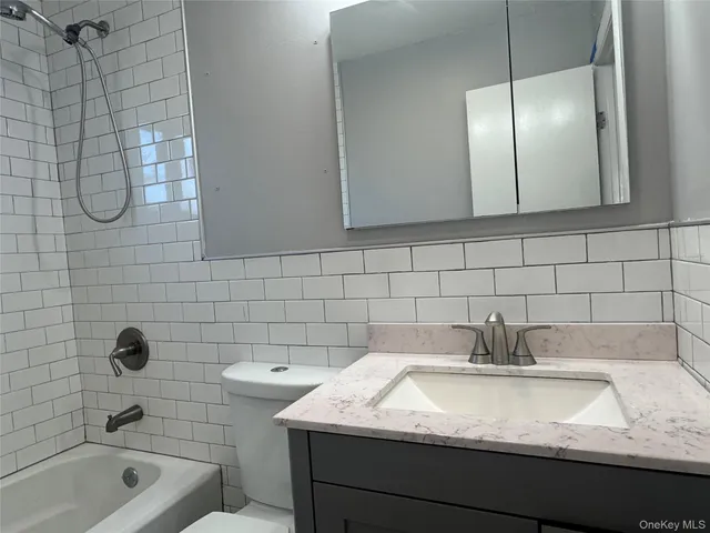 a bathroom with a granite countertop sink a toilet and shower