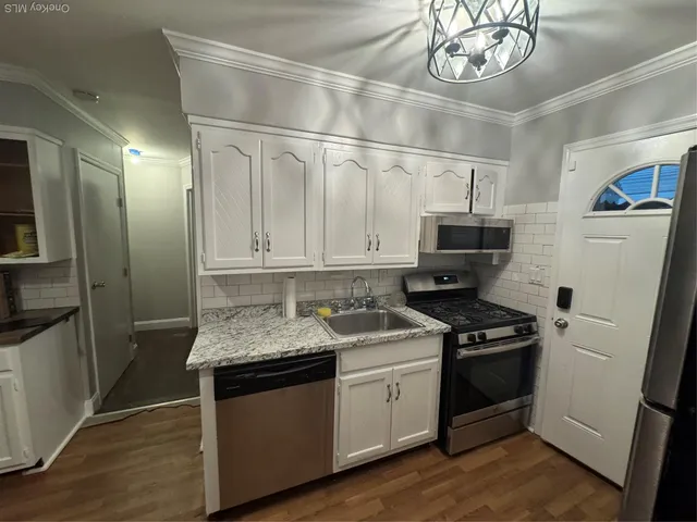 a kitchen with stainless steel appliances granite countertop a stove a refrigerator and a sink with wooden floor