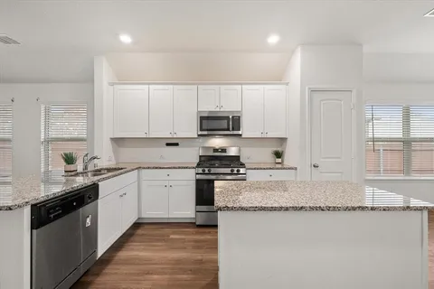 a large kitchen with granite countertop a stove top oven a sink a counter space and cabinets