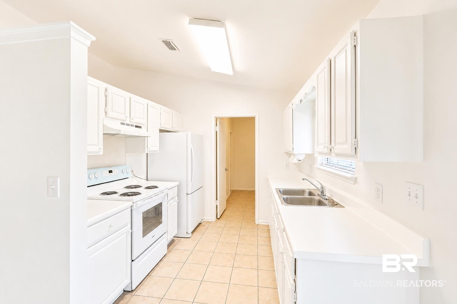 614 East Gate Circle Foley, AL 36535 - Photo 10 of 31 Galley kitchen featuring white cabinetry, solid surface countertops, a double basin stainless steel sink, tile flooring, and integrated white appliances
