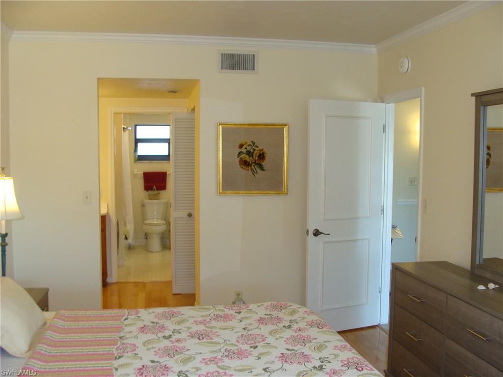 807 River Point Drive, Unit 201D Naples, FL 34102 - Photo 14 of 31 a bedroom with a bed and wooden floor