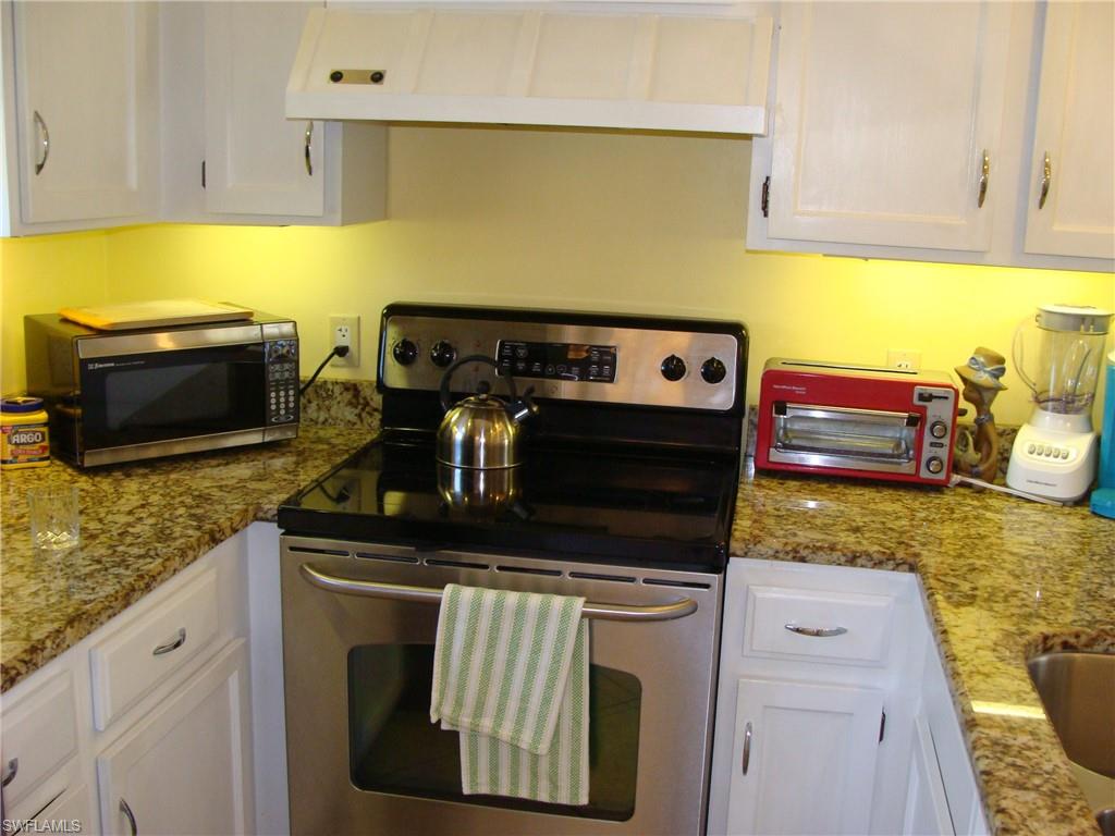 807 River Point Drive, Unit 201D Naples, FL 34102 - Photo 3 of 31 a kitchen with granite countertop a stove top oven a sink a counter space and cabinets
