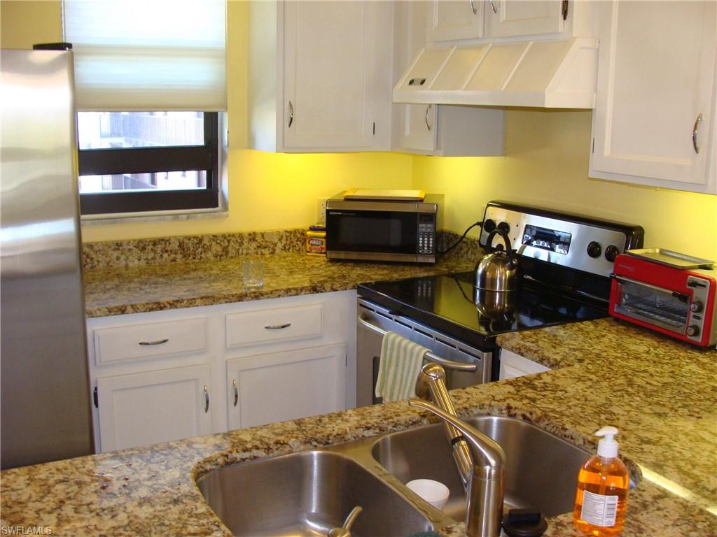 807 River Point Drive, Unit 201D Naples, FL 34102 - Photo 4 of 31 a kitchen with a sink a stove and cabinets