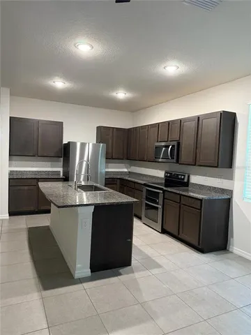 a kitchen with stainless steel appliances granite countertop a stove a sink and a microwave