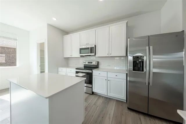 a kitchen with a refrigerator stove and white cabinets