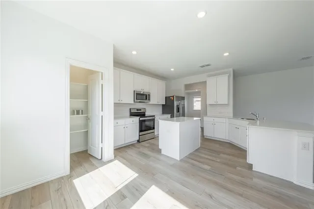 a large white kitchen with a refrigerator a sink dishwasher and a stove with wooden floor