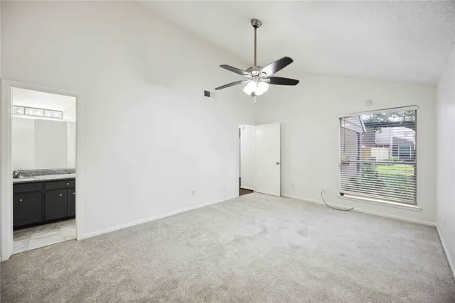 an empty room with chandelier fan and windows