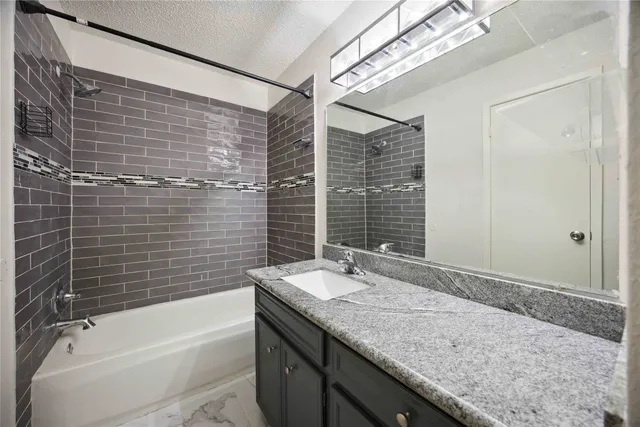 a bathroom with a granite countertop sink a toilet and bathtub