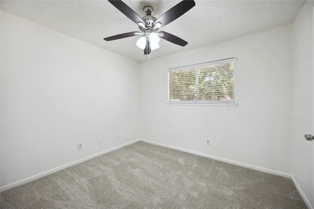 an empty room with a window and a fan