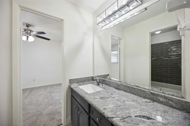 a bathroom with a granite countertop sink a mirror and shower