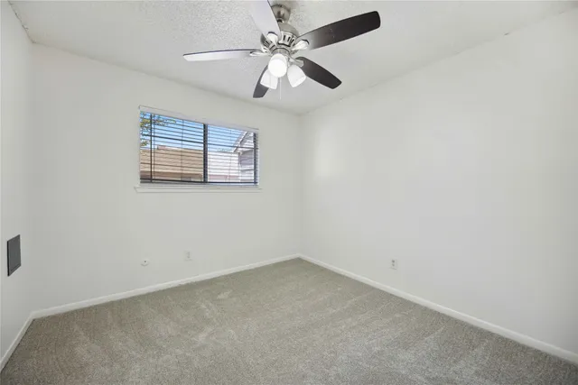 an empty room with a window and a fan