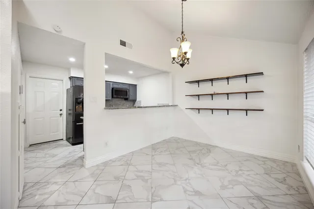 a view of a room with a kitchen and a chandelier fan
