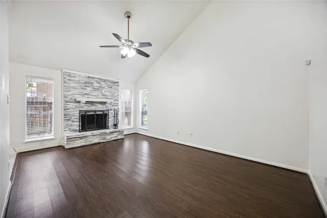 an empty room with wooden floor fireplace and fan
