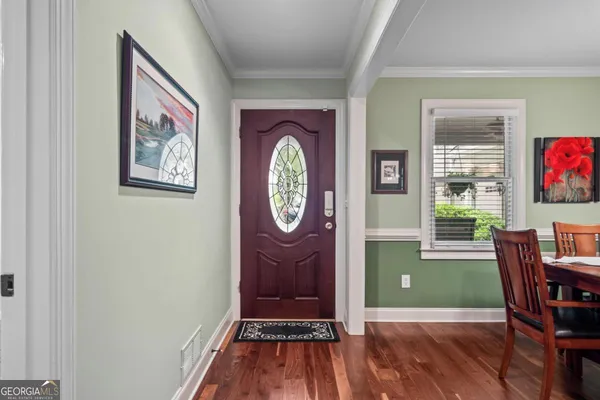 a dining room with wooden floor a chandelier a wooden table and chairs