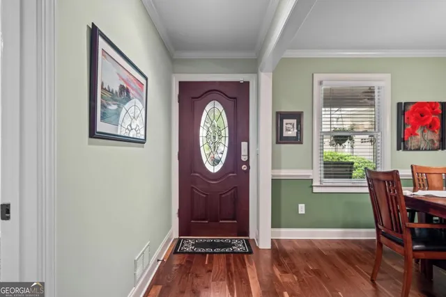a dining room with wooden floor a chandelier a wooden table and chairs