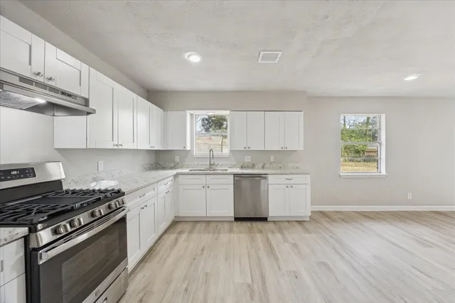 a kitchen with a stove a sink and wooden floor