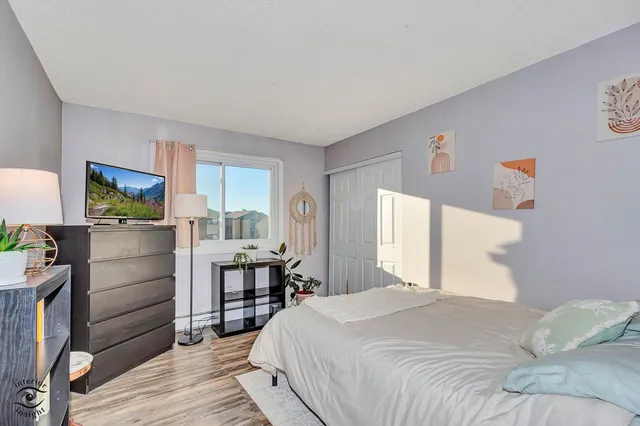 a bedroom with a bed and a flat tv screen on dresser
