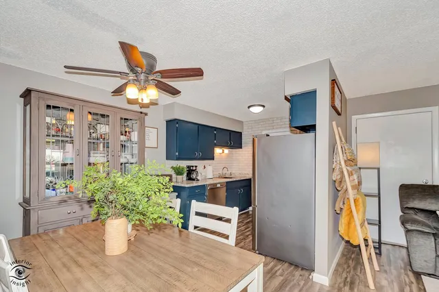 a kitchen with a refrigerator a stove a sink dishwasher a dining table and chairs with wooden floor