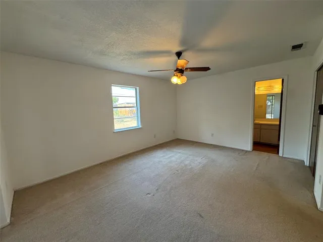 an empty room with a window and chandelier fan