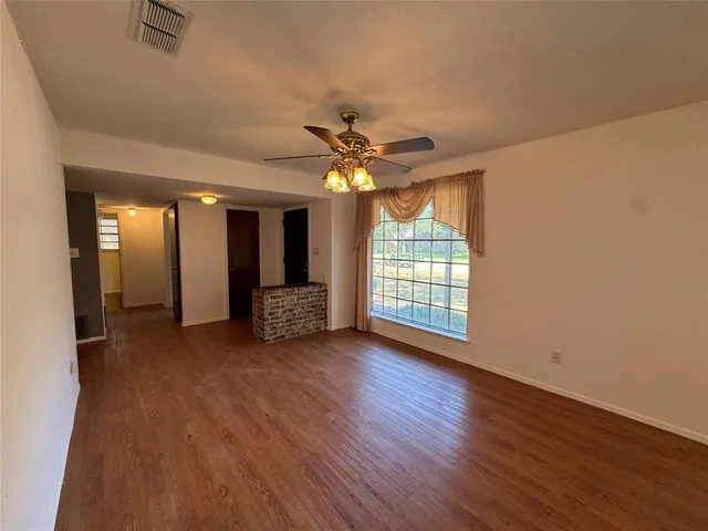 an empty room with wooden floor and a ceiling fan