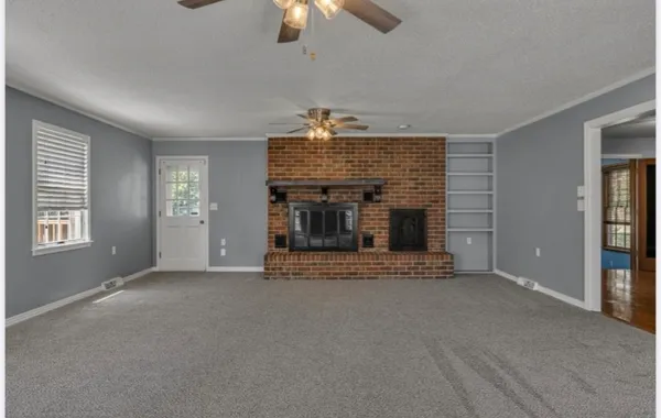 a view of an empty room with fireplace and a window