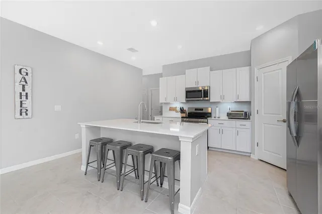 a kitchen with a sink a microwave a refrigerator and white cabinets
