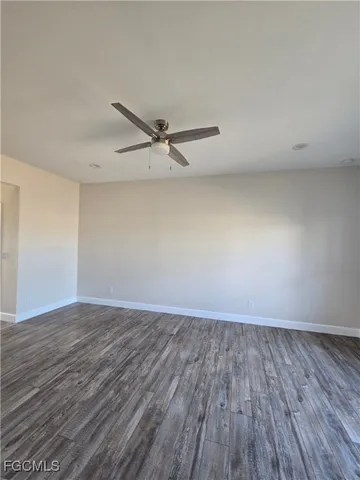 a view of an empty room with wooden floor and a ceiling fan