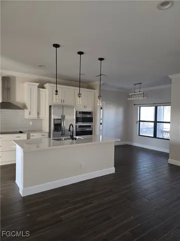 a view of kitchen with stainless steel appliances granite countertop a stove a sink a window and wooden floor