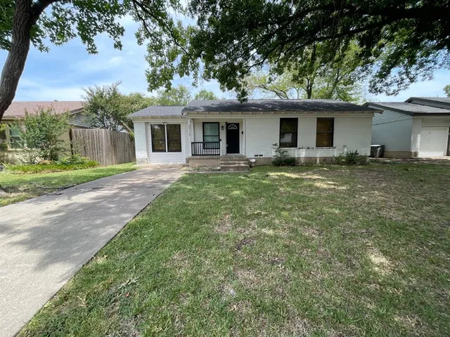a front view of a house with a garden and trees