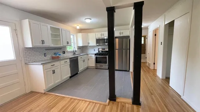 a kitchen with stainless steel appliances granite countertop a refrigerator a sink dishwasher a stove and white countertops with wooden floor