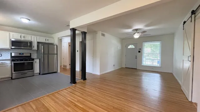 a view of a kitchen with wooden floor electronic appliances and windows