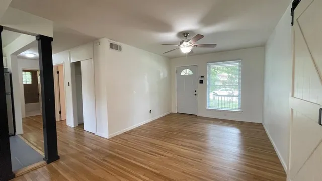 a view of an empty room with wooden floor and a window