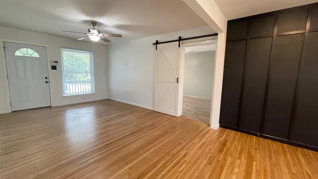 a view of an empty room with wooden floor and a window