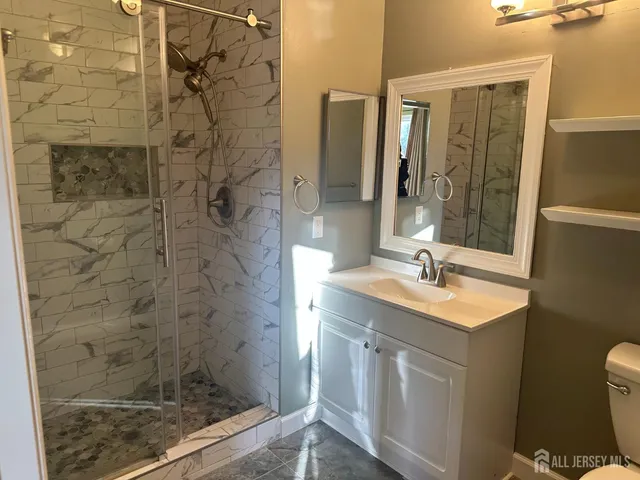 a bathroom with a sink a toilet a mirror and shower