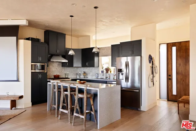 a kitchen with stainless steel appliances a refrigerator a stove a sink and chairs