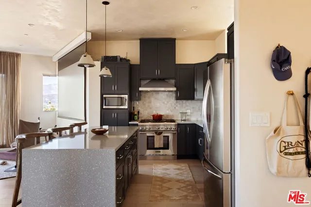 a kitchen with stainless steel appliances granite countertop a refrigerator a stove and a sink with wooden floor