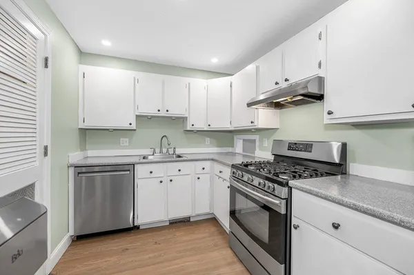 a kitchen with granite countertop white cabinets and stainless steel appliances