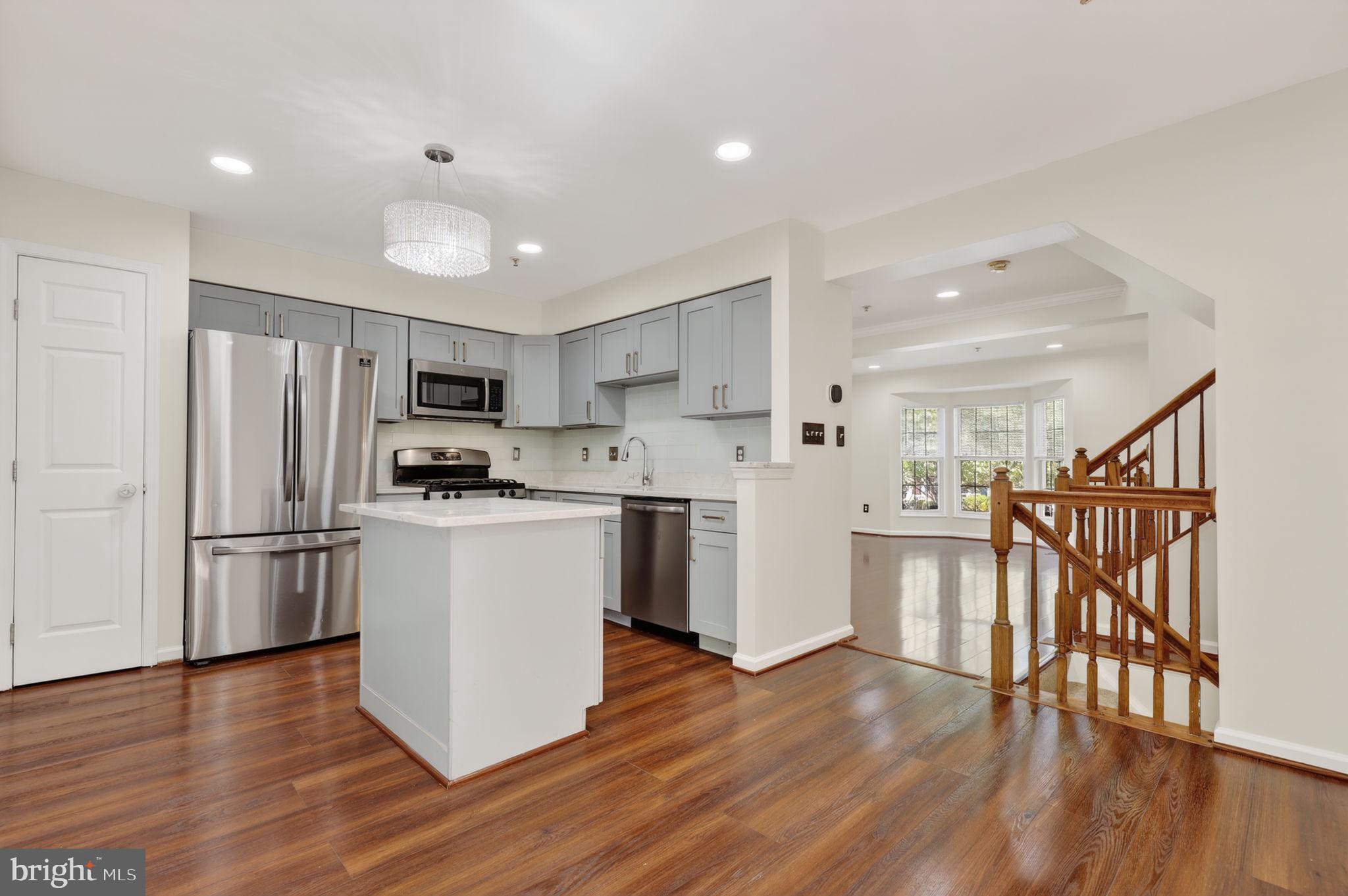 8612 Fire Rock Road Laurel, MD 20724 - Photo 15 of 57 a kitchen with a refrigerator a stove top oven and a dining table with wooden floor