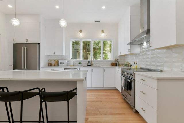 a kitchen with a sink a stove a refrigerator and white cabinets with wooden floor