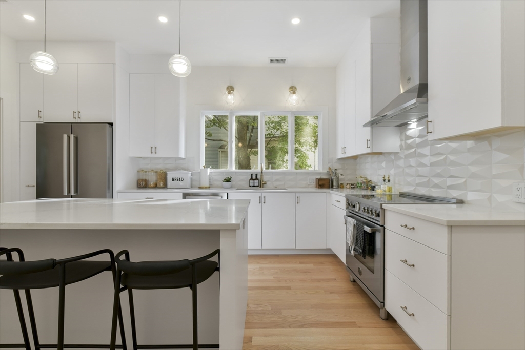 26 Bartlett Avenue Arlington, MA 02476 - Photo 15 of 27 a kitchen with a sink a stove a refrigerator and white cabinets with wooden floor