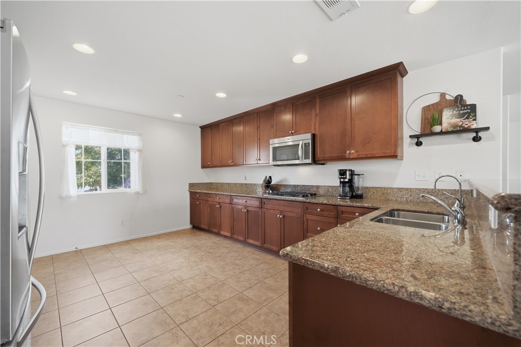 3439 Joshua Tree Court Perris, CA 92570 - Photo 25 of 49 a kitchen with a sink a stove a microwave a counter top space and cabinets