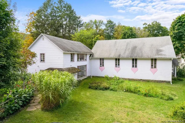 a backyard of a house with plants and large tree