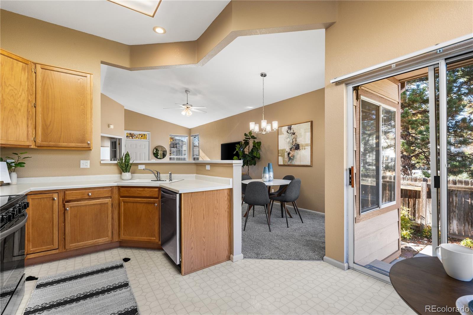 12799 East Wyoming Circle Aurora, CO 80012 - Photo 19 of 44 a kitchen with stainless steel appliances granite countertop a refrigerator a sink dishwasher a stove and a dining table with wooden floor